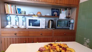 A kitchen with a microwave, toaster, and a bowl of fruit on the counter. - La Terrazza di Anna (Sassari)