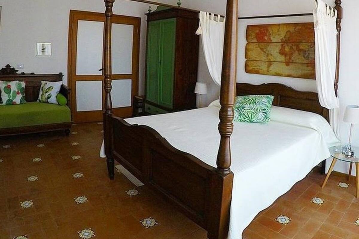 Une chambre avec un lit à baldaquin, un canapé vert, une armoire en bois et une porte verte.