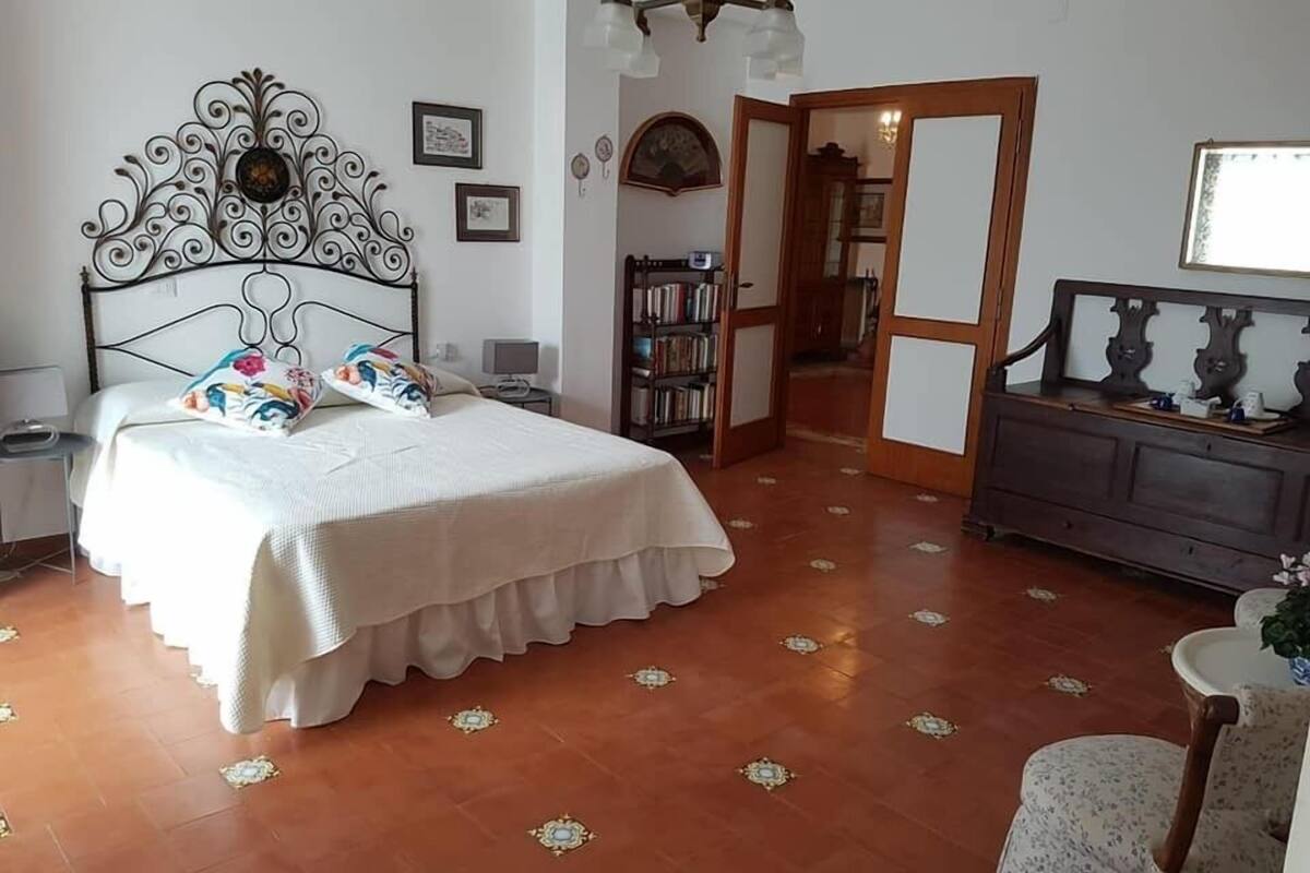 Une chambre à coucher comprenant un lit, une table de chevet, une bibliothèque et une commode.