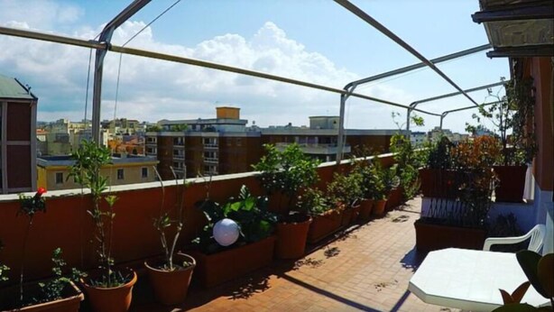 A rooftop terrace with potted plants, a table, and a view of the cityscape. - La Terrazza di Anna (Sassari)