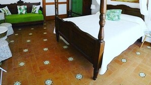 A four-poster bed with a wooden frame, a green sofa, a small round table, and a green wardrobe. - La Terrazza di Anna (Sassari)