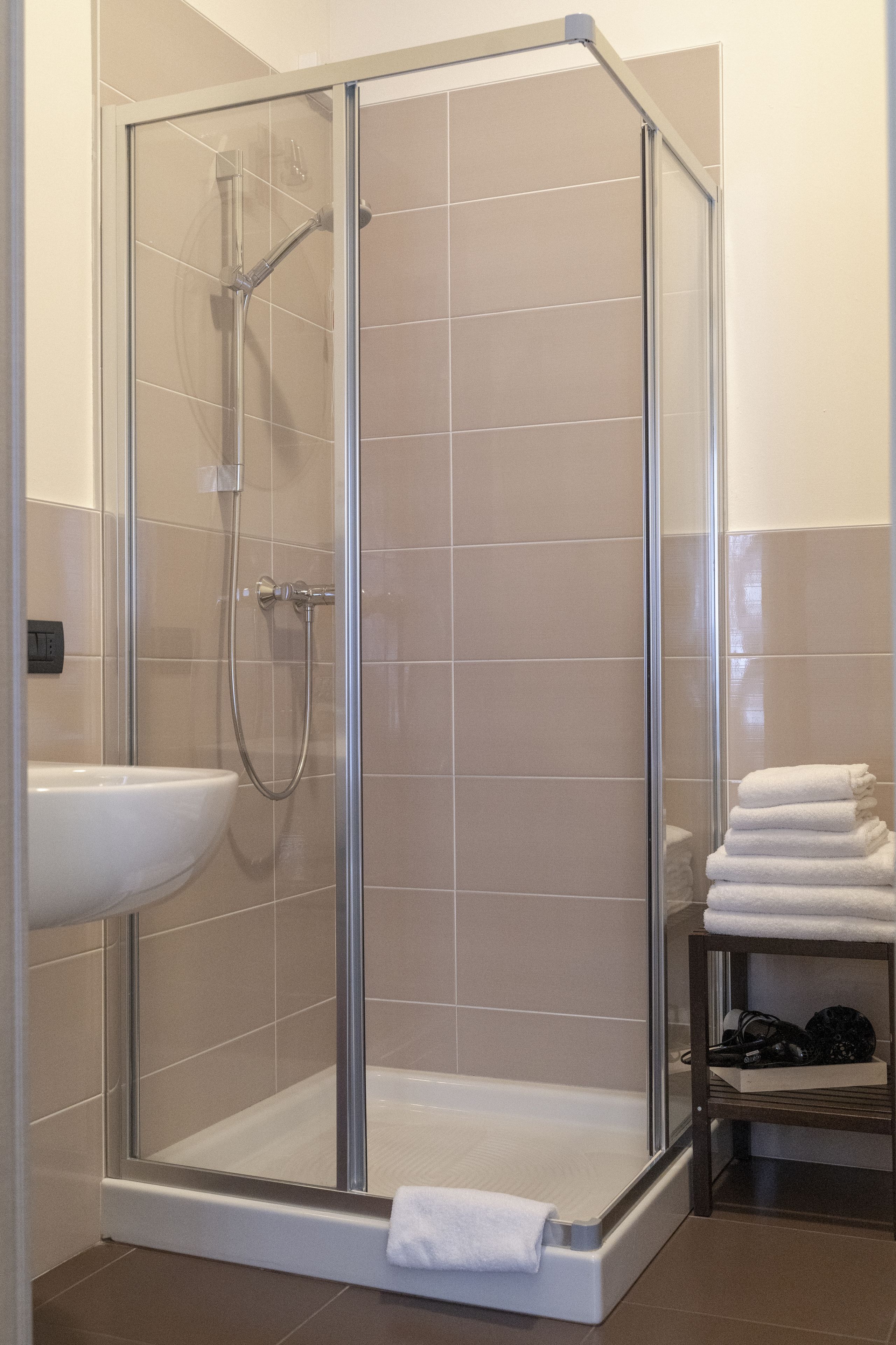 A glass-enclosed shower area with a white sink and a towel rack.