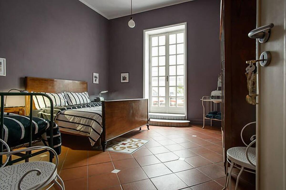Un dormitorio con cama, una silla, una ventana y una puerta.
