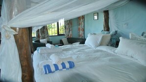 A bedroom with a bed, pillows, a chair, and a window. - Pumzika Tu (Kwale)