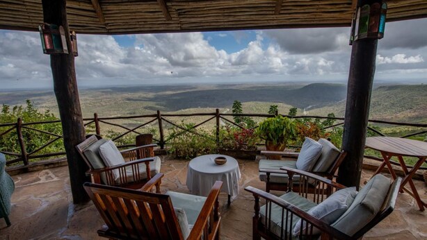 A covered outdoor seating area with wooden furniture and a view of the landscape. - Pumzika Tu (Kwale)