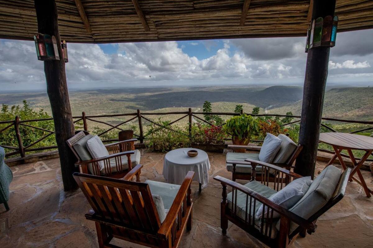 A covered outdoor seating area with wooden furniture and a view of the landscape.