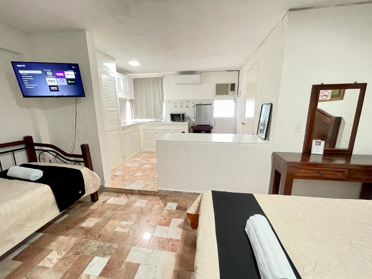 Une chambre d’hôtel avec deux lits, une télévision, une kitchenette et une salle de bain.