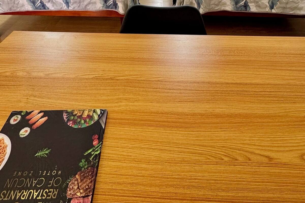 A hotel room with two single beds, a wooden table, and a book on the table.