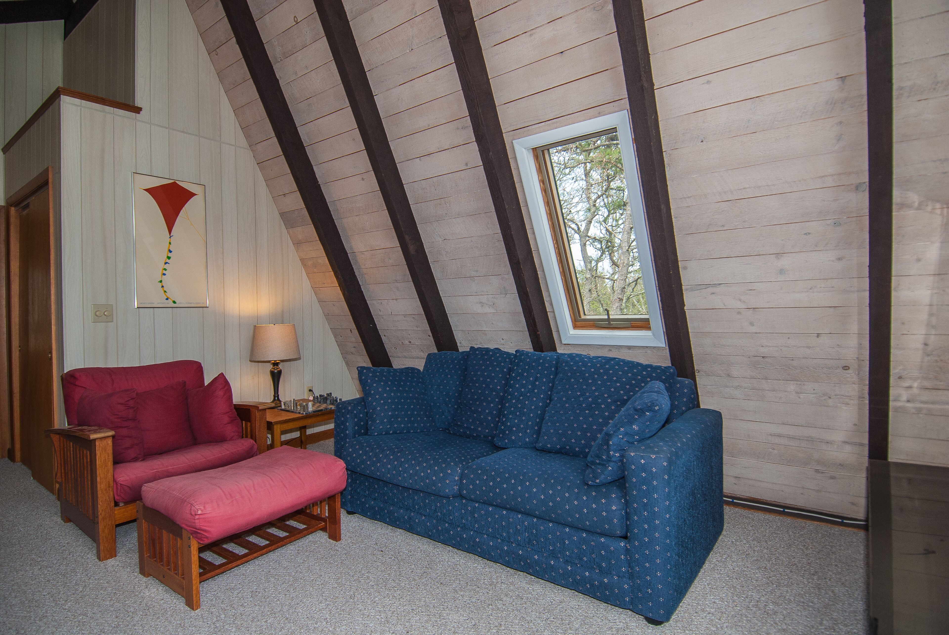 Ein Zimmer mit einem blauen Sofa, einem roten Sessel und einer hölzernen Bank.