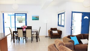 A spacious living area with a dining table, two sofas, and a lamp. - Sirina Villa STN 29 (Paralimni)