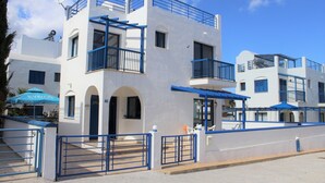A white building with blue balconies and a gated entrance. - Sirina Villa STN 29 (Paralimni)