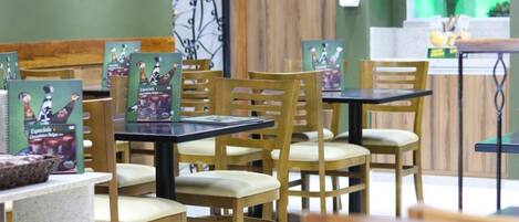 Een restaurantinterieur met houten stoelen en tafels, waarvan sommige een menukaart hebben.
