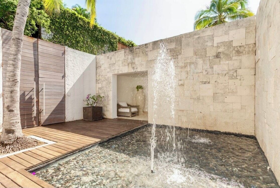 Ein Wellnessbereich mit Wasserspiel, Holzterrasse und Steinwand.