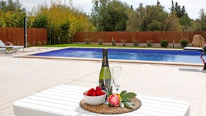 A poolside setting with a table, a bottle of champagne, a glass, and a bowl of strawberries. - COZY HOLIDAY VILLA IN THE HEART OF MALLORCA (Sa Pobla)
