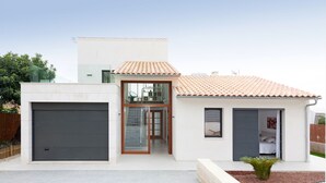 A modern two-story house with a garage, a glass door entrance, and a small garden area. - COZY HOLIDAY VILLA IN THE HEART OF MALLORCA (Sa Pobla)