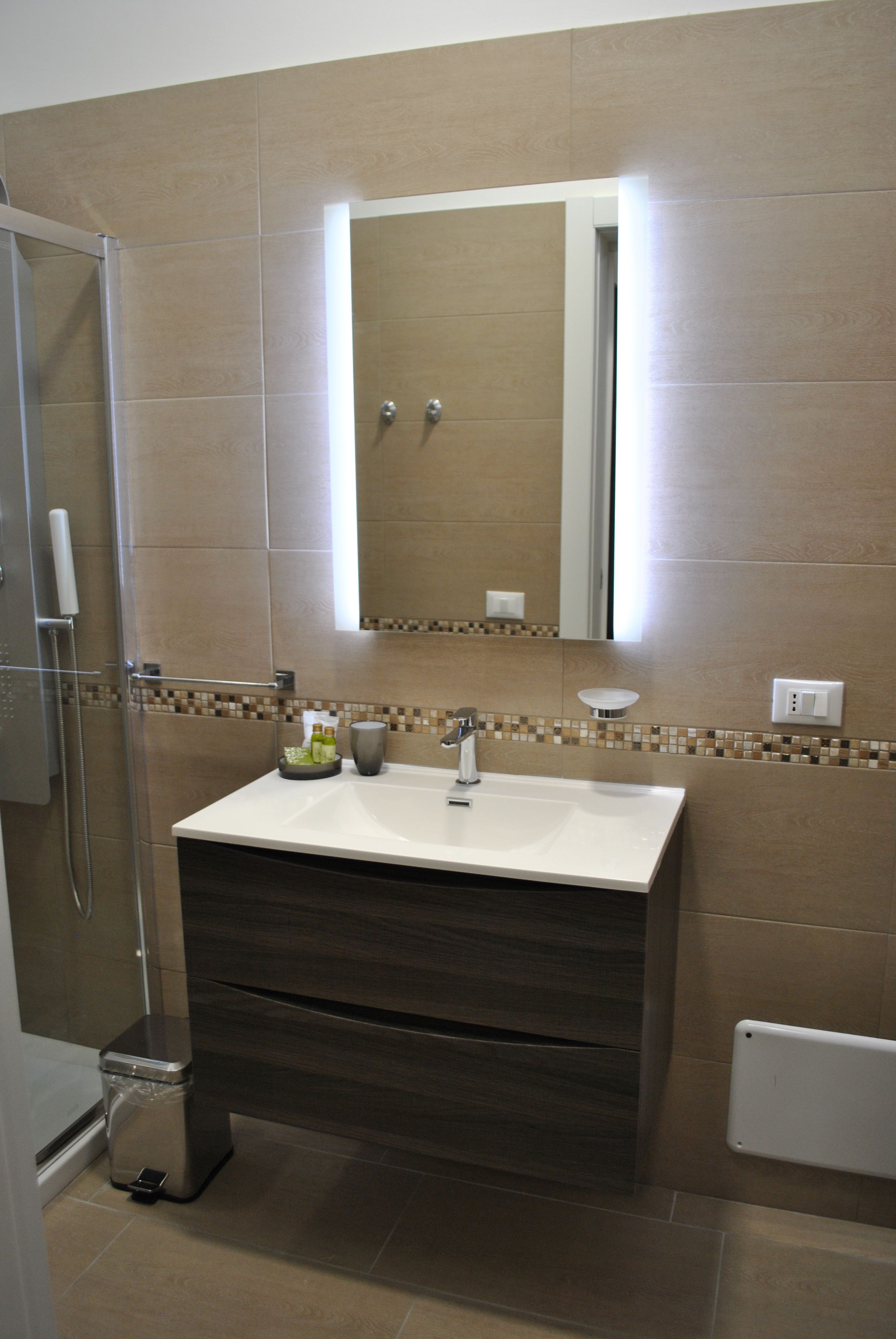 Ein Badezimmer mit Dusche, Waschbecken und Spiegel.