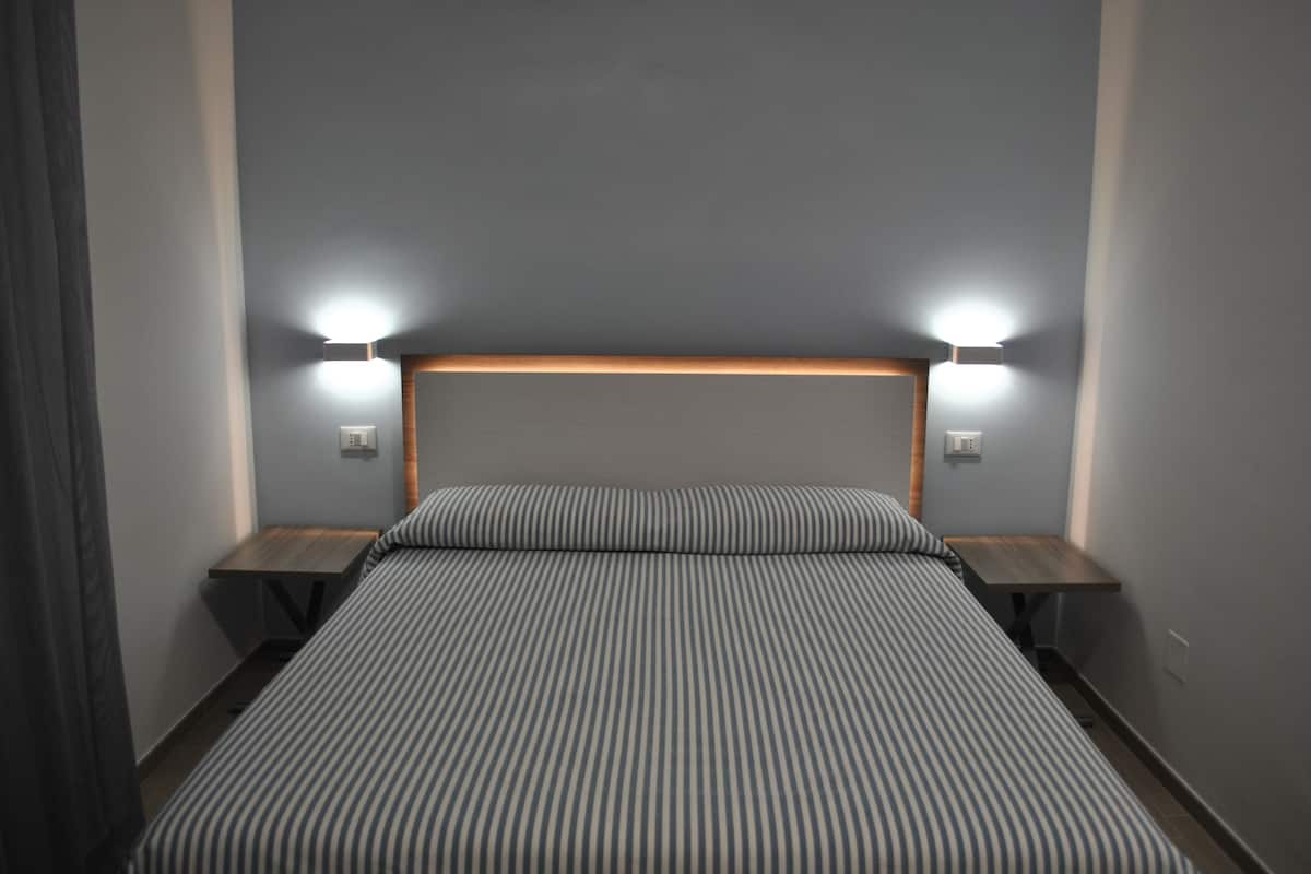 Ein Hotelzimmer mit einem großen Bett, zwei Nachttischen und zwei Wandleuchten.