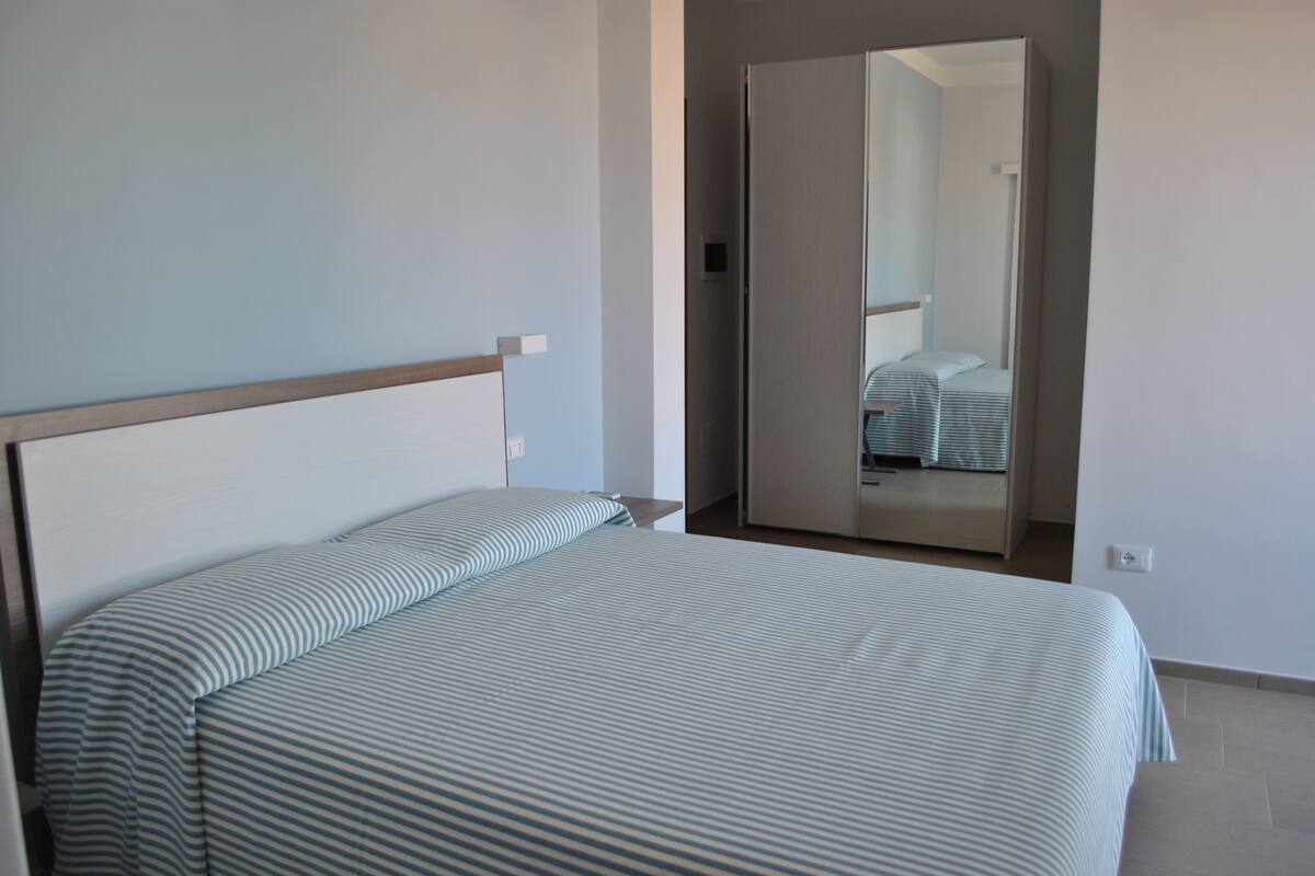 Ein Schlafzimmer mit Bett, Schrank und Spiegel.