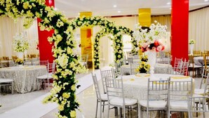 Un salón de banquetes con mesas redondas, sillas blancas y decoración floral.