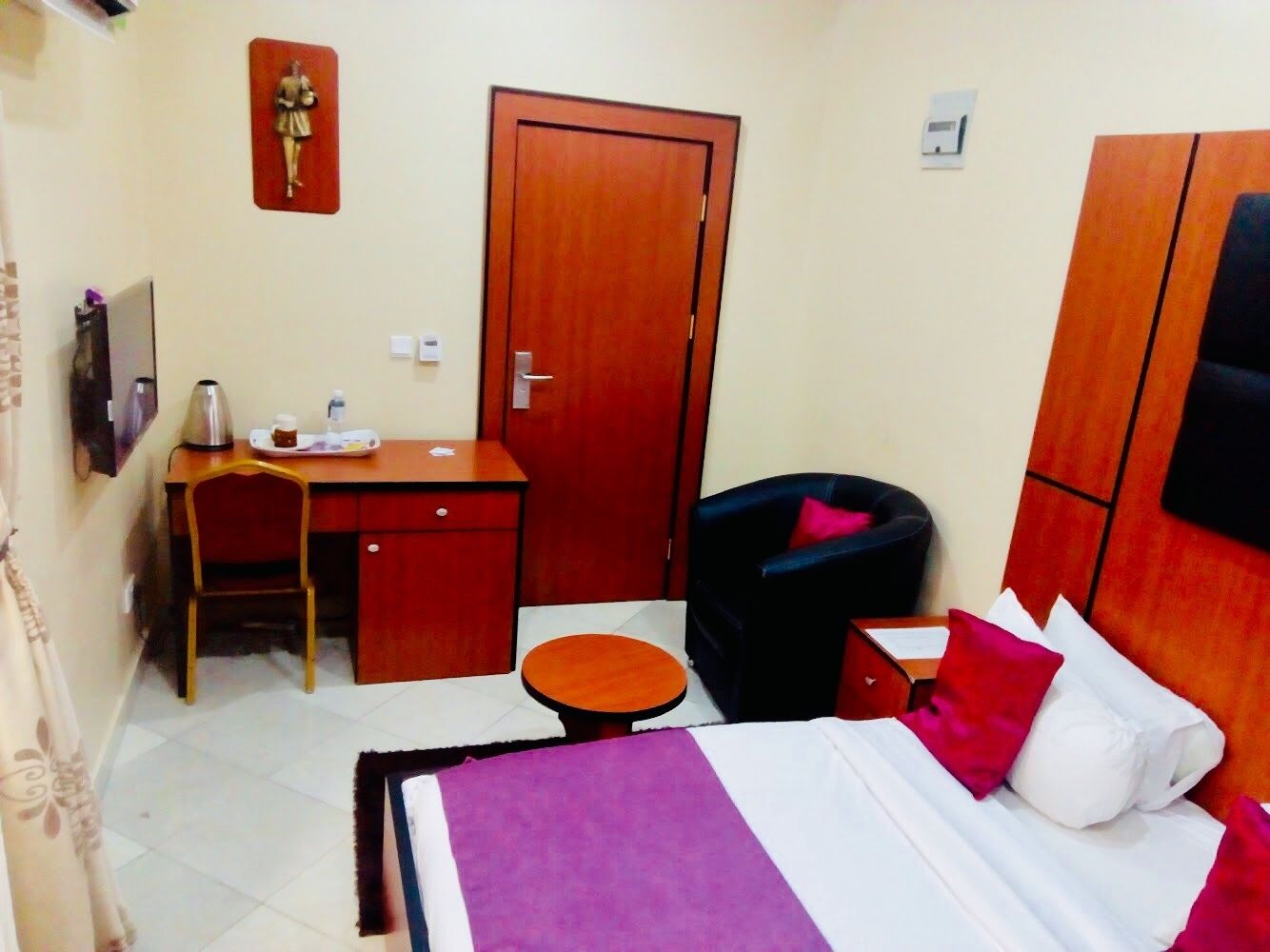 Una habitación de hotel con cama, escritorio, silla, una mesita y un armario.