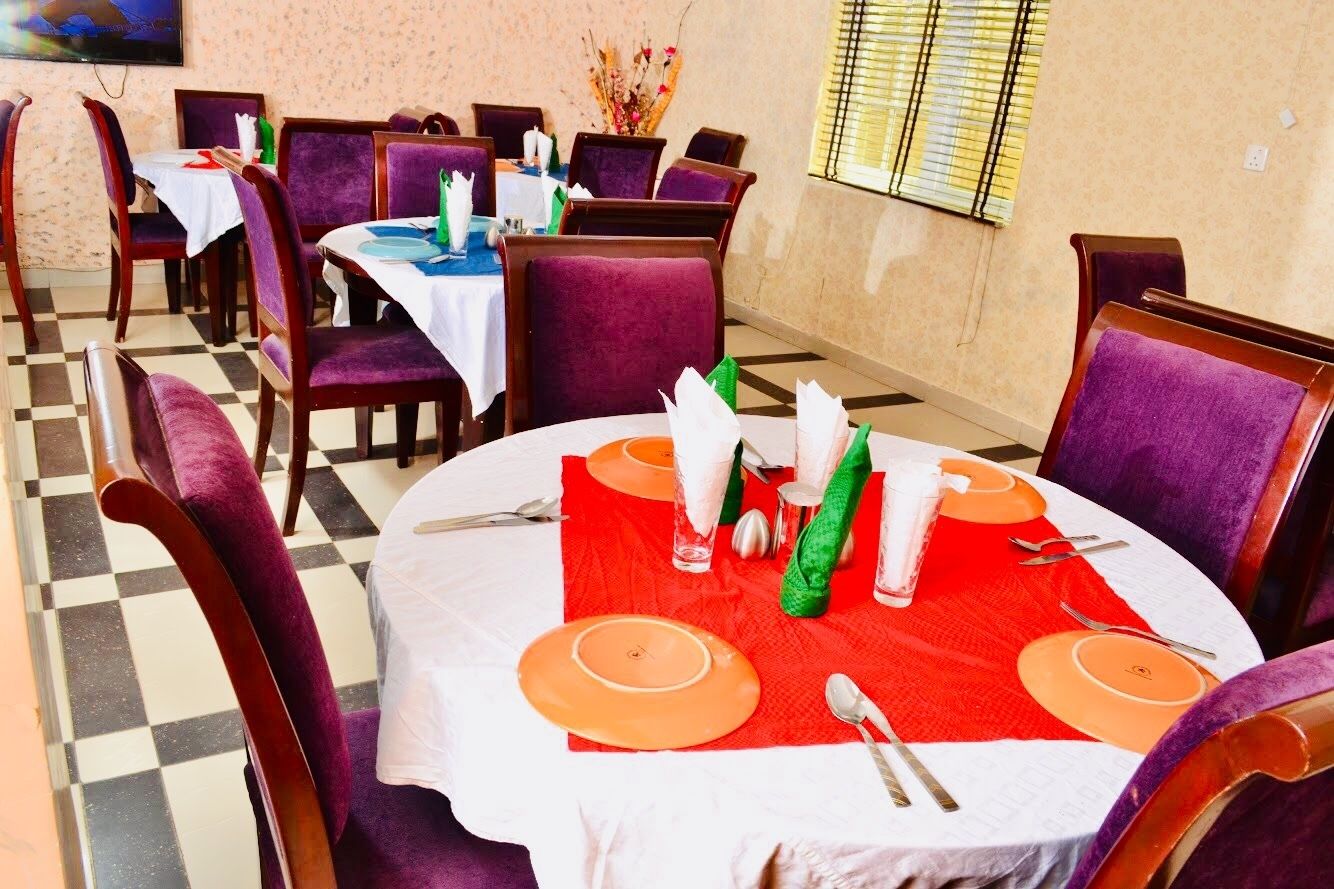 A restaurant with round tables, purple chairs, and a checkered floor.
