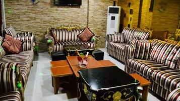 A living room with striped sofas, a coffee table, and a flat-screen TV mounted on the wall.