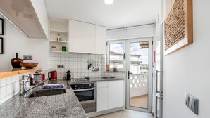 A modern kitchen with white cabinets, granite countertops, and a built-in oven. There is a window with a view of the outside.