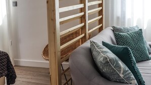 A room with a bunk bed, grey sofa, and patterned pillows.