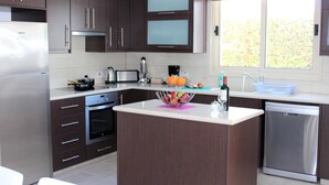 Una cocina moderna con armarios de madera oscura, electrodomésticos de acero inoxidable y una isla central con un frutero.