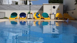 Una piscina con sillas flotantes amarillas y verdes, y un patito inflable blanco.