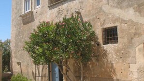 A stone building with a small tree in front, a blue door, and a window with a cross on the wall. - A holiday home in the Iblea countryside a stone's throw from the sea (Ragusa)