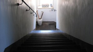 A narrow stairway leading to a landing with a small window, a white vase with brushes, and a metal handrail. - A holiday home in the Iblea countryside a stone's throw from the sea (Ragusa)