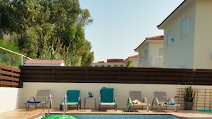 Une piscine avec des chaises longues et un matelas gonflable vert.