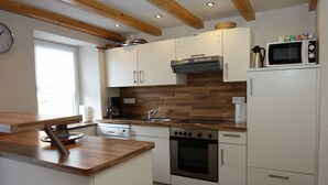 Una cocina con encimeras de madera, armarios blancos y un horno empotrado, además de un microondas sobre un gabinete blanco.