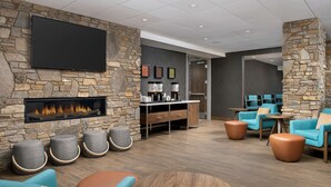 A modern lounge area with a stone wall, a fireplace, comfortable seating, and a flat-screen TV.