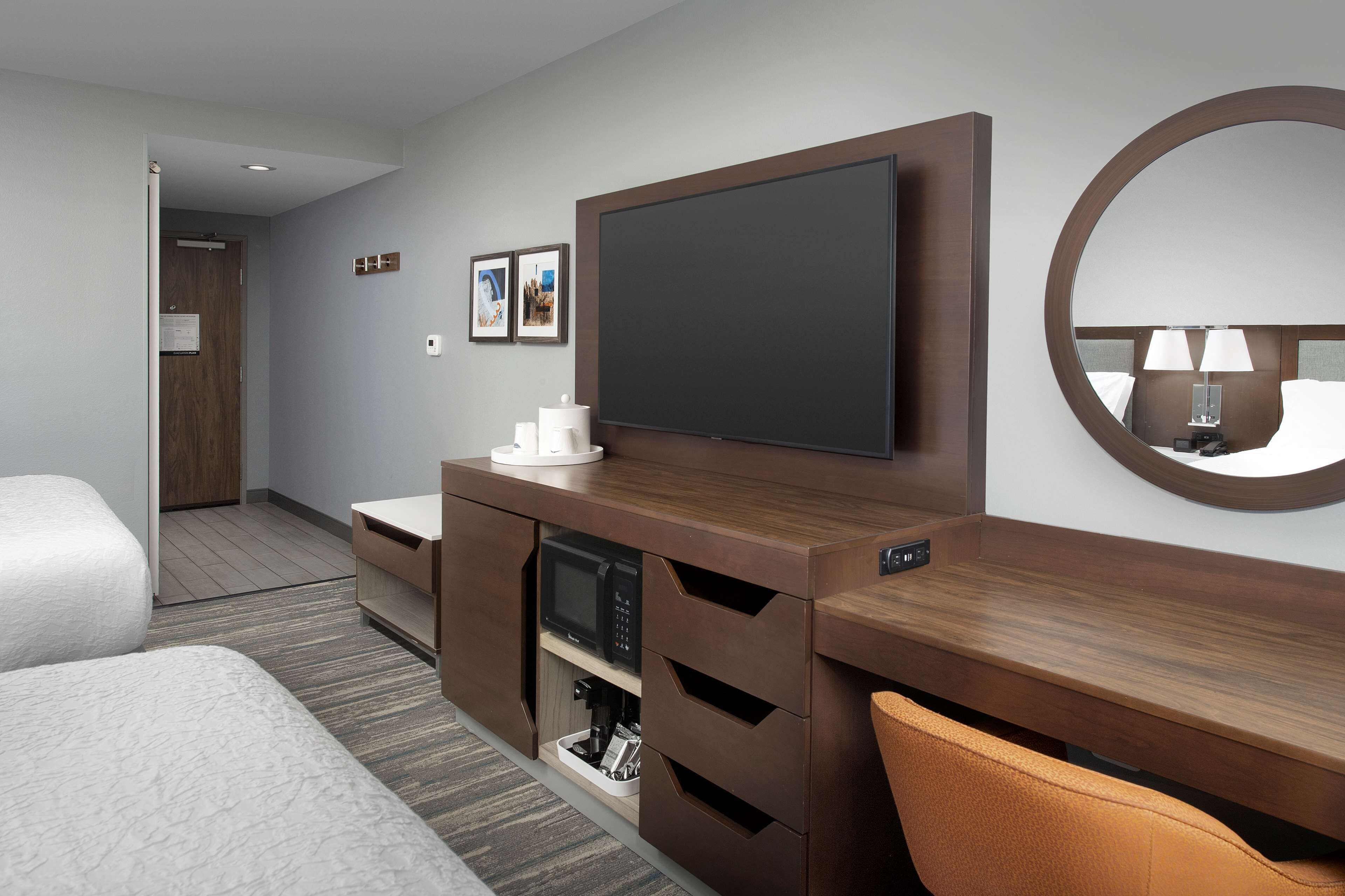 A hotel room with a bed, a desk with a flat-screen TV, a microwave, and a coffee maker.