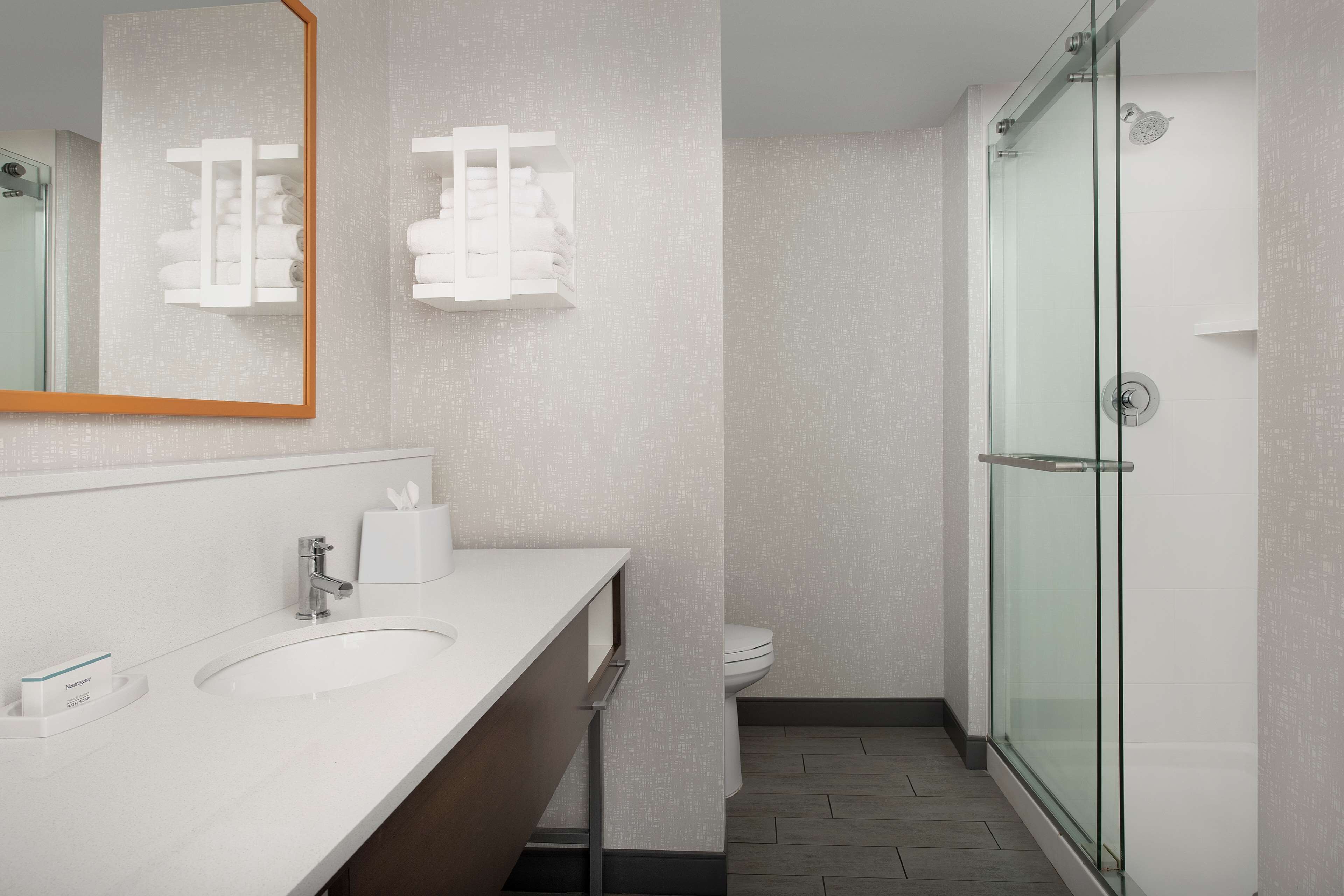 Un baño moderno con lavamanos blanco, un espejo, cabina de ducha de vidrio y un inodoro.