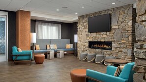 A modern lounge area with a stone wall, a flat-screen TV, a fireplace, and comfortable seating.