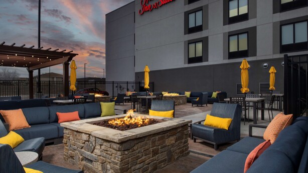A hotel patio with outdoor seating, a stone fire pit, and umbrellas.