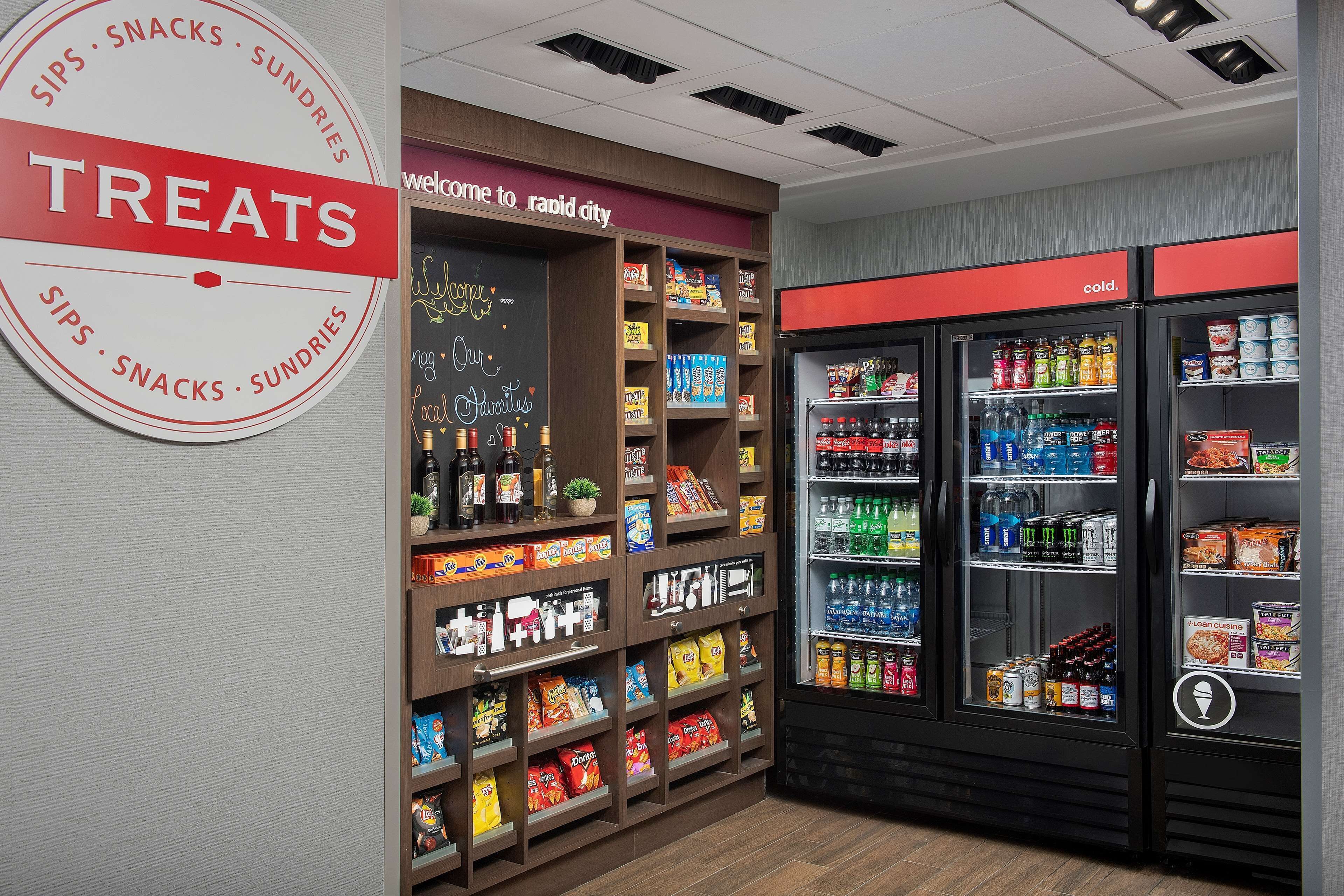 A treats section in a store with shelves of snacks and a refrigerated display with beverages.