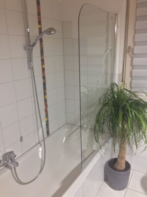 Een bad/douchecombinatie, een haardroger, handdoeken, zeep