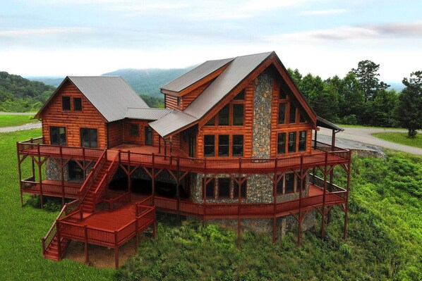 A log cabin with a balcony and a stone fireplace.