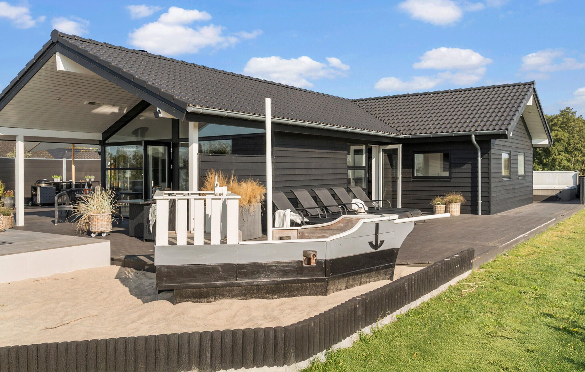 A modern house with a covered patio area, outdoor seating, and a small pool.