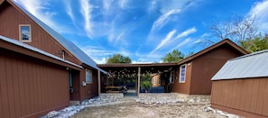 A covered outdoor area with stone pathways, wooden buildings, and string lights. - Fantastic Pool, Hot Tub, Cabana, Mt. Views, Party Pavilion, 2 Minutes 2 Frio! (Concan)
