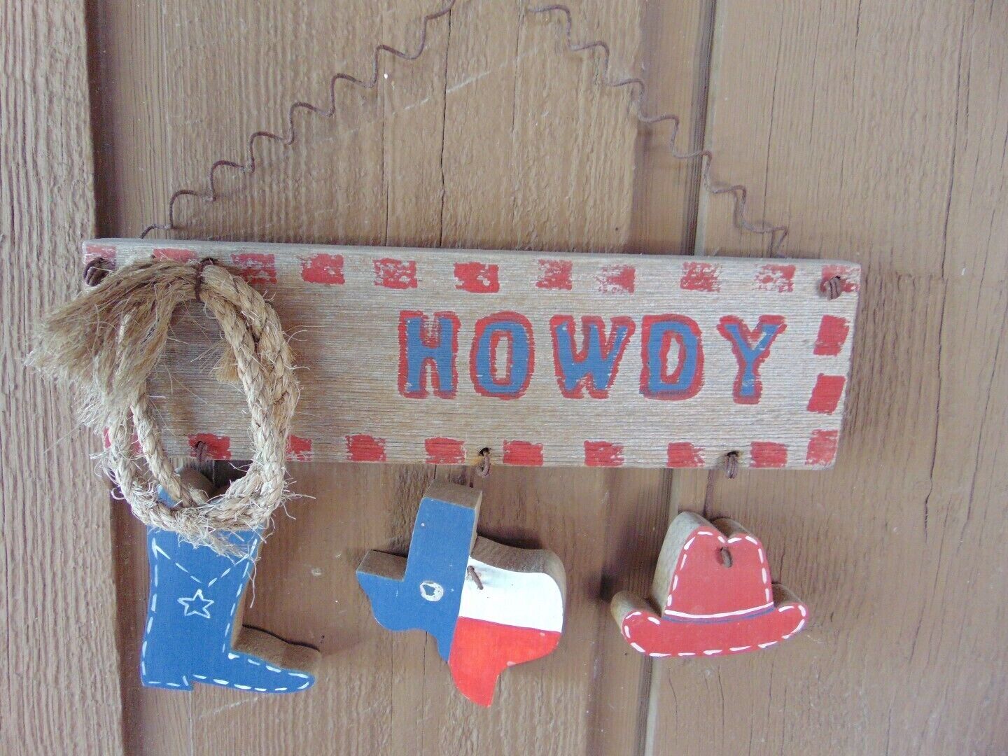 A wooden sign with the word "HOWDY" in red and blue letters, a blue Texas flag, and a red and white cowboy hat.