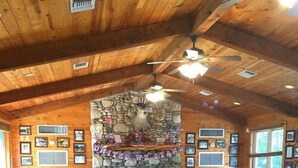 A rustic wooden interior with stone fireplace, wooden tables and chairs, and framed pictures on the walls. - Fantastic Pool, Hot Tub, Cabana, Mt. Views, Party Pavilion, 2 Minutes 2 Frio! (Concan)