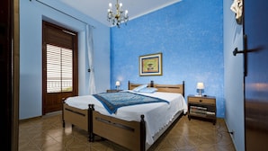Une chambre à coucher avec un lit, une table de chevet, un lustre et une porte avec une fenêtre.