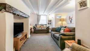 A living room with a television, two sofas, a wooden coffee table, and a fireplace.