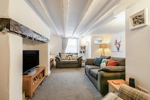 A living room with a television, two sofas, a wooden coffee table, and a fireplace.