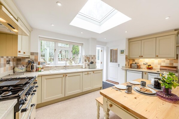 A modern kitchen with a skylight, a large island, and a dining area.